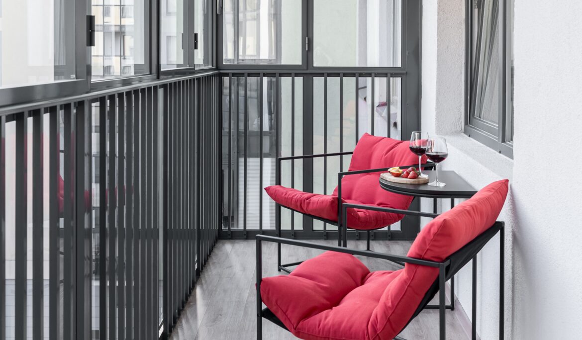 Dubai narrow enclosed balcony design with red lounge chairs and black railing — DubaiRenovate